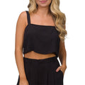 Woman wearing a black Tori Linen Tank with wide straps, cropped fit, styled for beach casual comfort.
