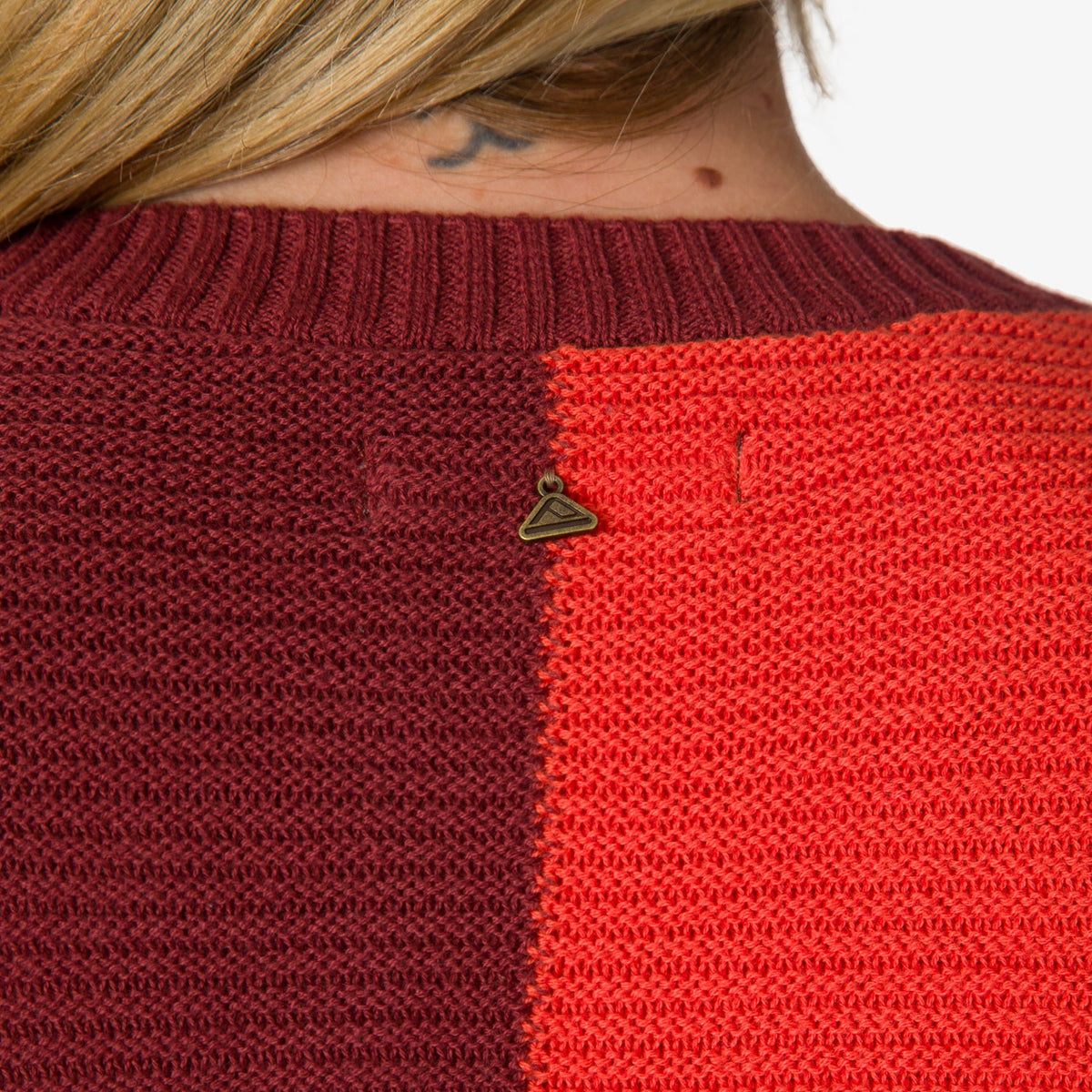 Close-up of the back neckline of the Carrie Sweater showing knit texture in maroon and orange colors.