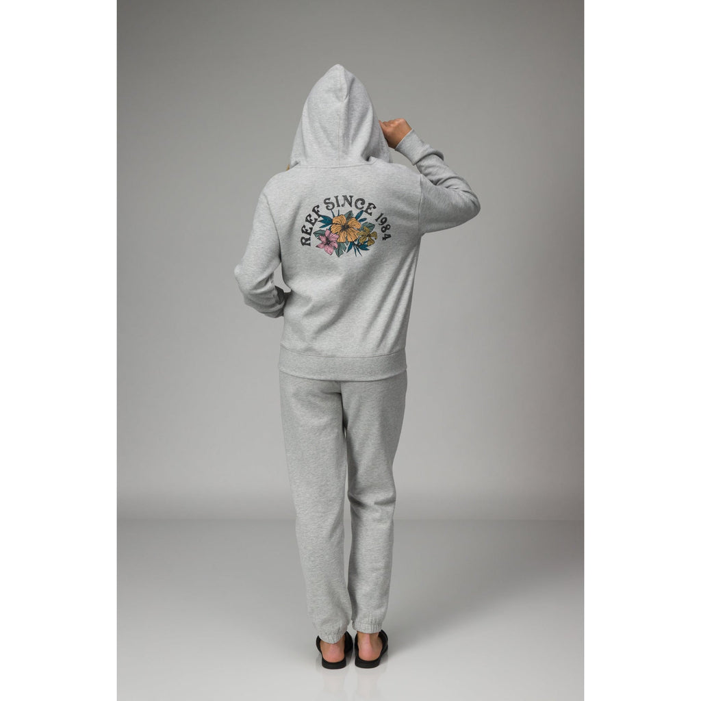 Rear view of a person wearing the Brittany Fleece Full Zip hoodie, featuring soft gray fabric and a floral REEF logo print.