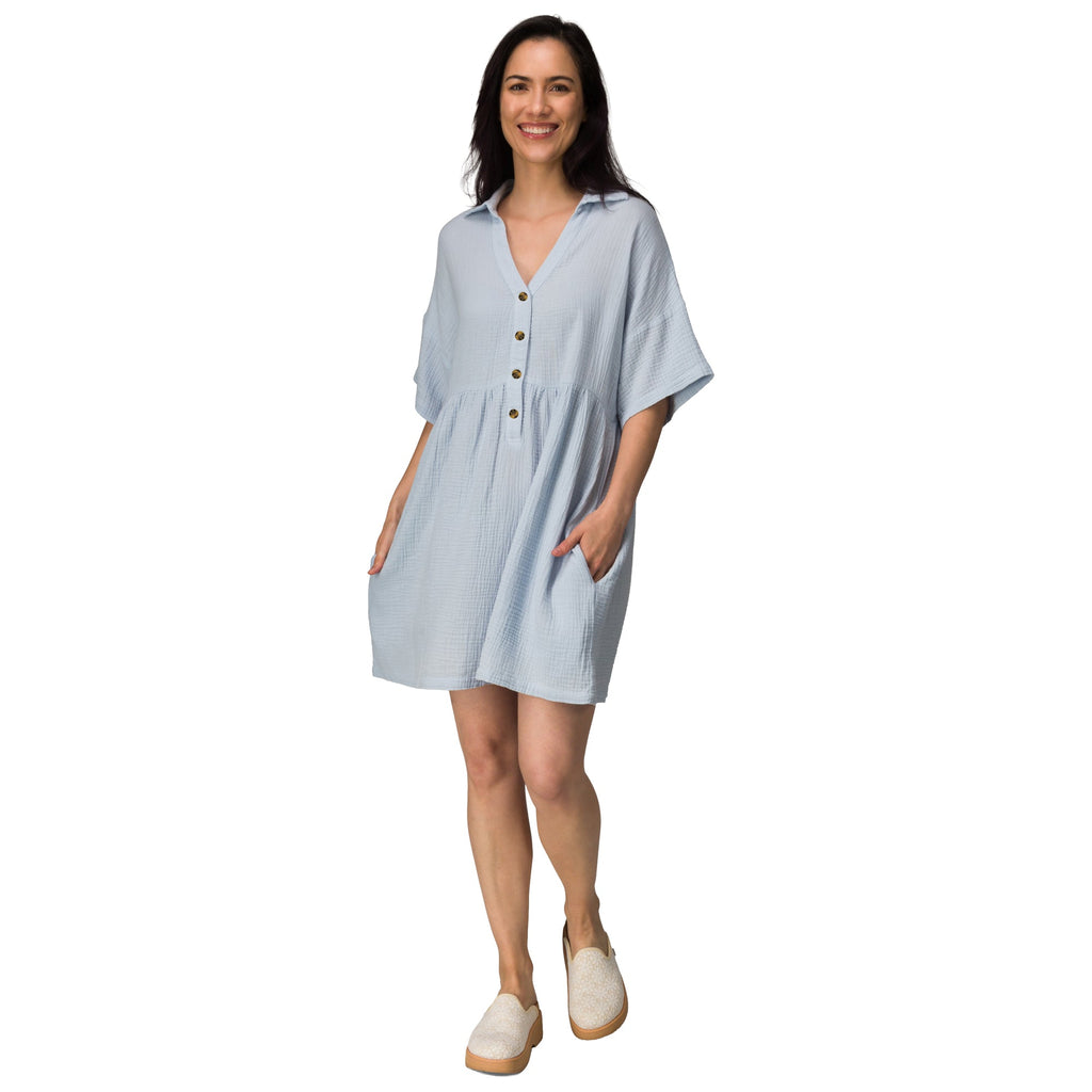 Woman wearing light blue Lainey Shirt Dress with buttons, side pockets, and slip-on shoes facing forward, beach-inspired comfort apparel.