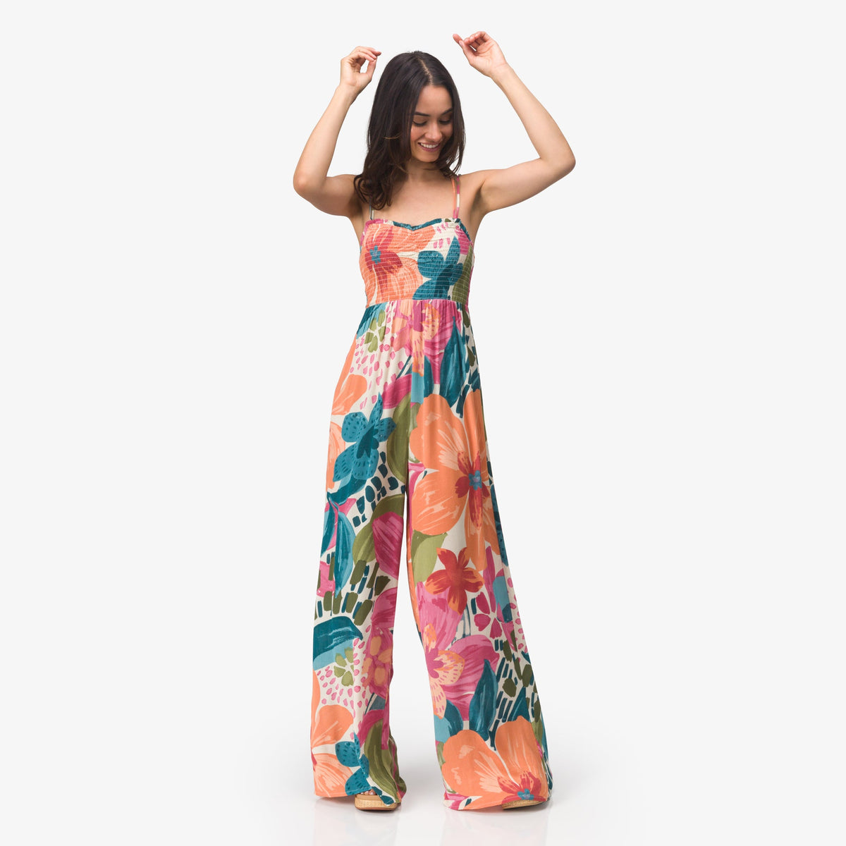 Woman wearing Eve Wide Leg Romper with colorful floral print, standing and smiling in a relaxed pose.