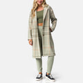 Woman wearing Beverly Knit Trench in desert sage plaid, facing front, showcasing long plaid trench coat with relaxed fit.