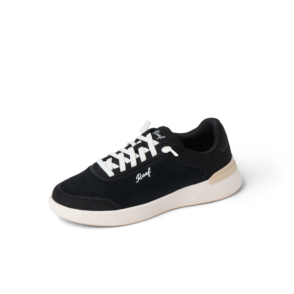 Shoreline Palisades women’s sneaker facing right with breathable black mesh upper and cushioned white sole for beach comfort
