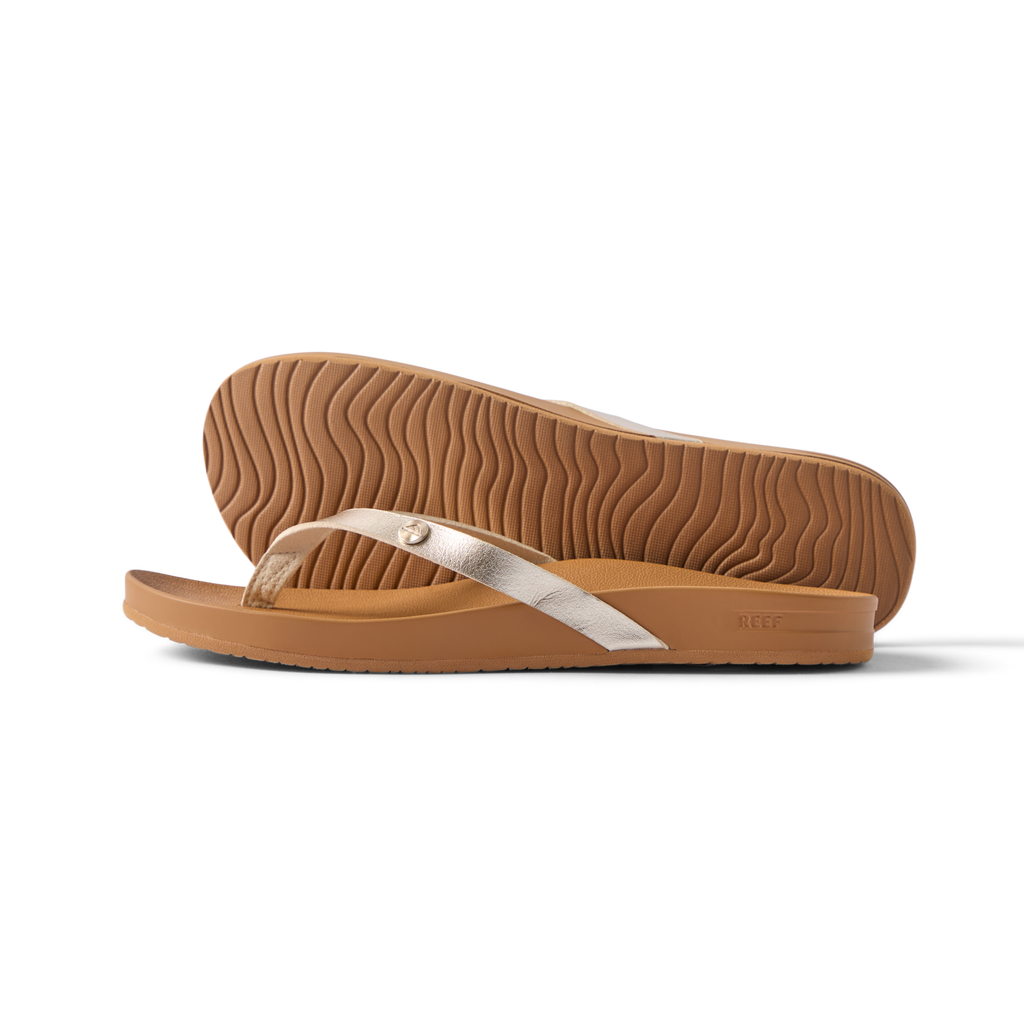 Vista Ivy women's gold flip flop shown from side with textured sole, designed for comfort and beach lifestyle.