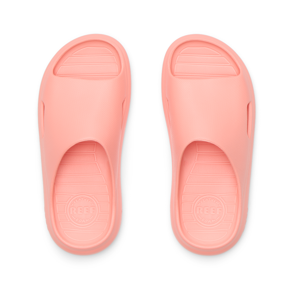 Top view of coral Kids Rio Slide unisex sandals showing molded footbed and soft-rebound cushioning for beach comfort