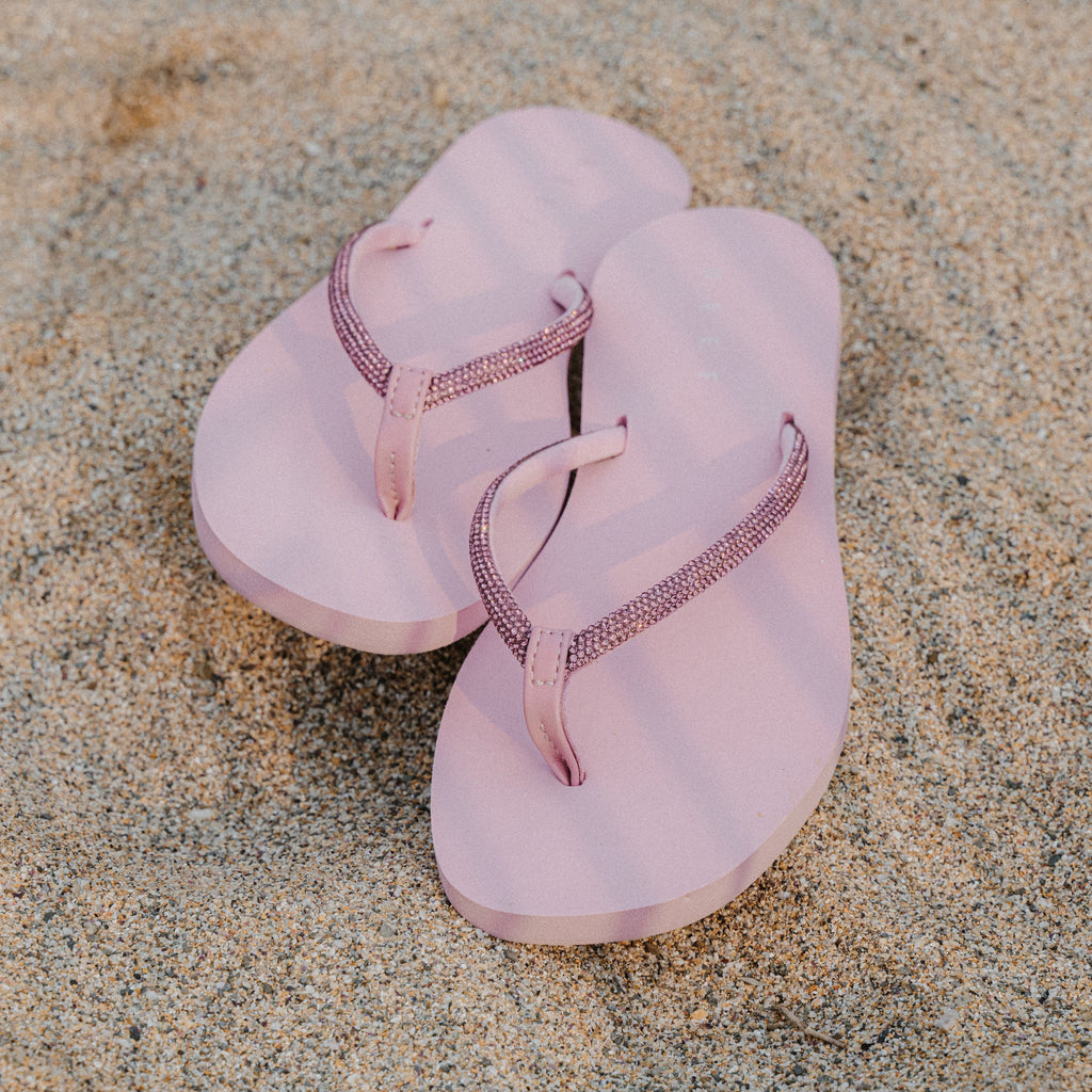 Bliss Bling Fling sandals facing forward, close-up of pink platform sandals with sparkling straps on sand beach