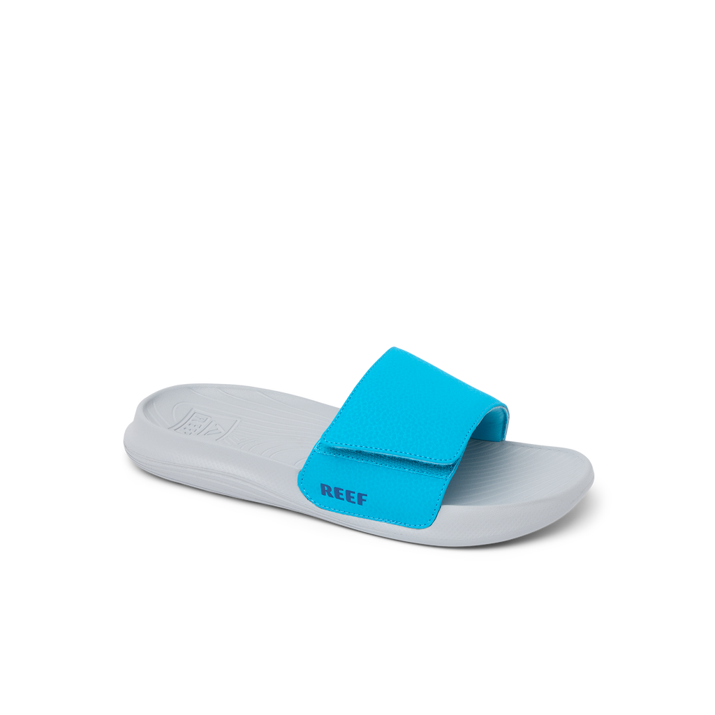 Kids Salty Slide sandal facing right with grey sole and bright blue adjustable strap, featuring comfort and arch support.