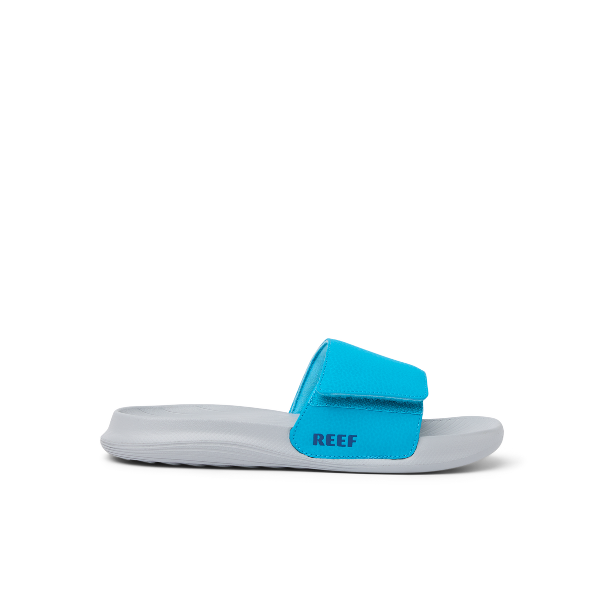 Kids Salty Slide facing left, close-up on side view showing blue strap with REEF logo, lightweight and water-friendly design.