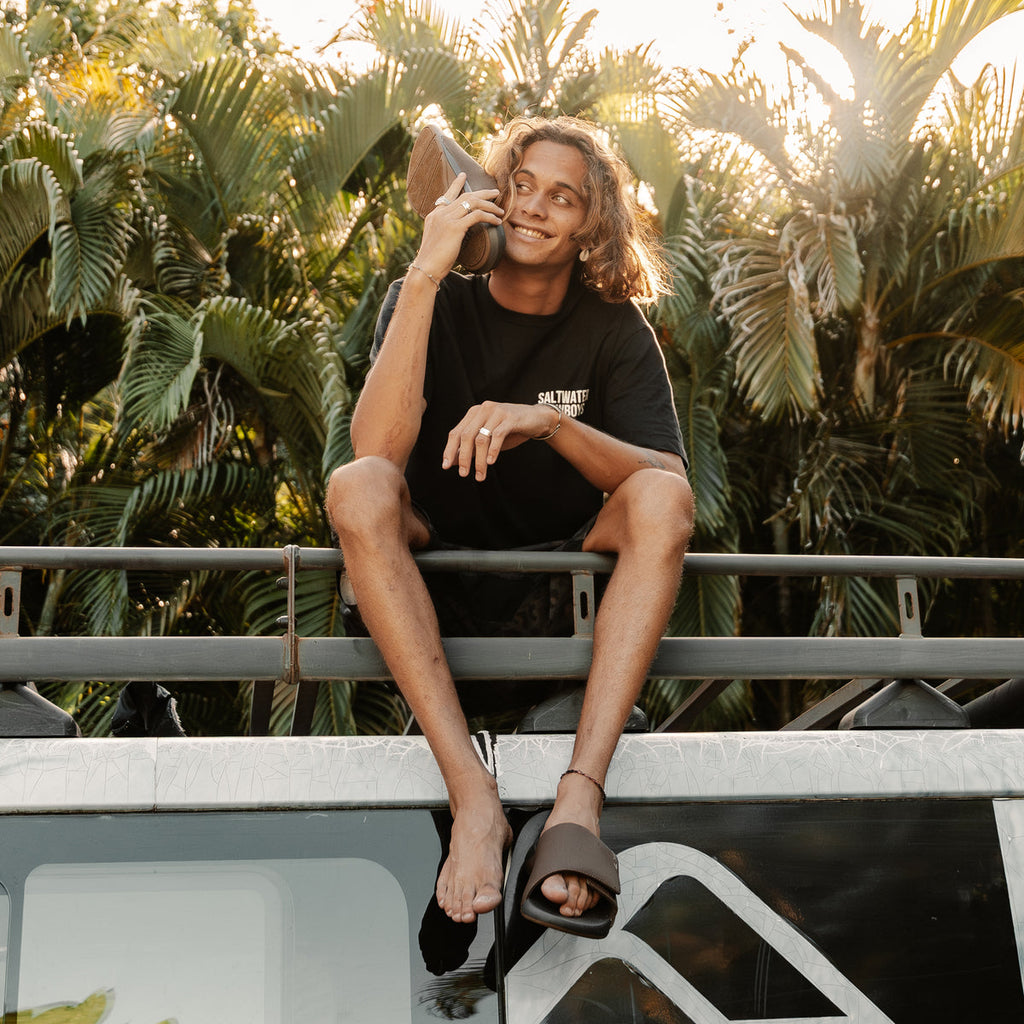 Man wearing black and grey Cruiser Slide facing forward, showing cushioned footbed and open toe design in outdoor setting.