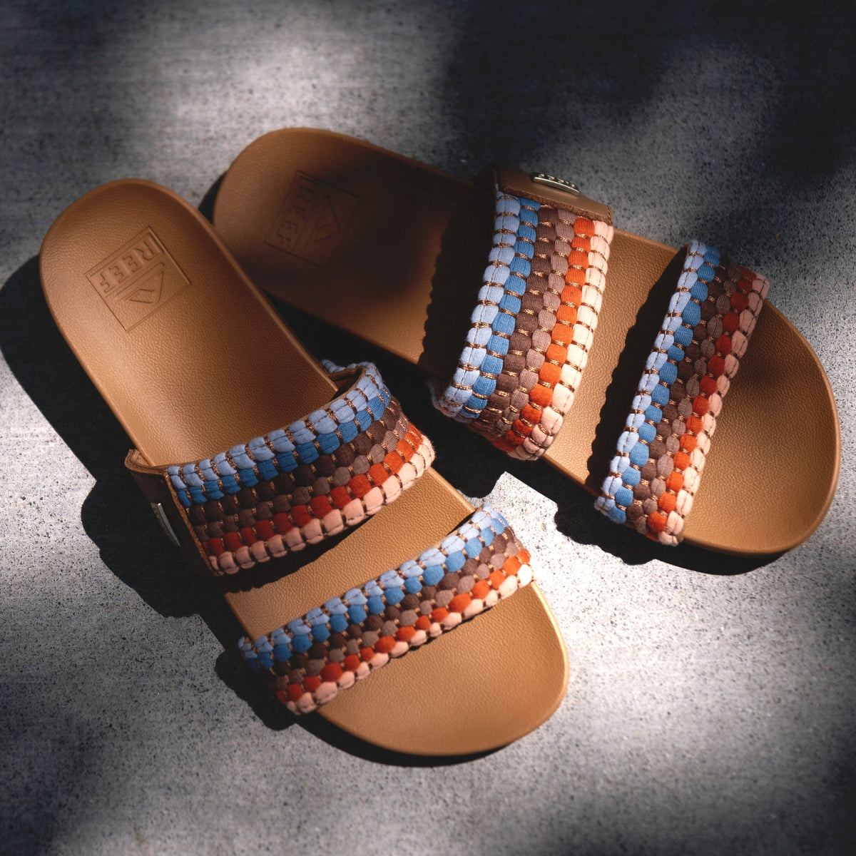 Pair of Cushion Vista sandals facing forward showing woven straps in blue, red, and brown with soft cushioning and arch support.