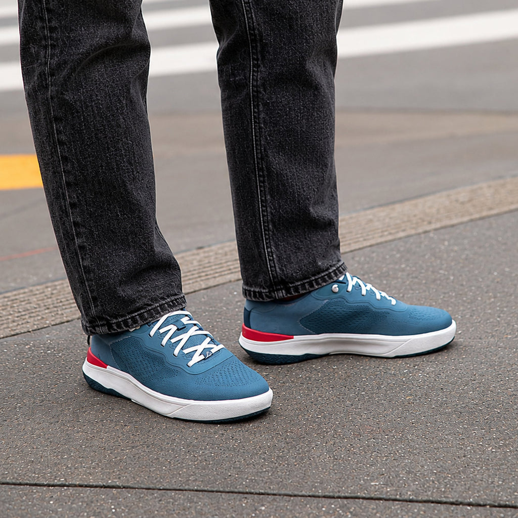 Shoreline Del Mar facing right on feet, men's blue sneaker with cushioned sole, elastic laces, and red-white accents for comfort.