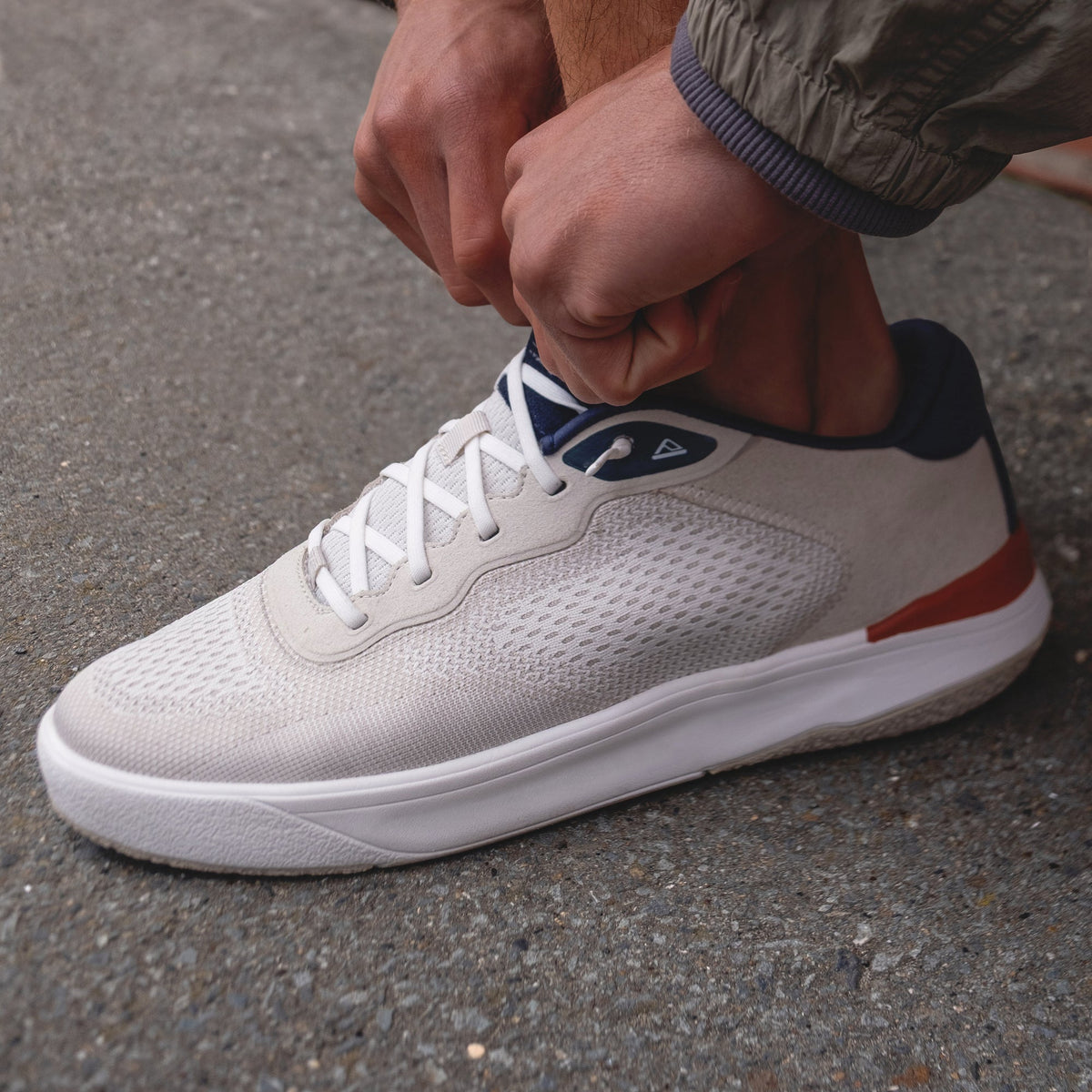 Shoreline Del Mar sneaker facing right, breathable tan knit upper with navy collar, white sole, tying elastic laces.
