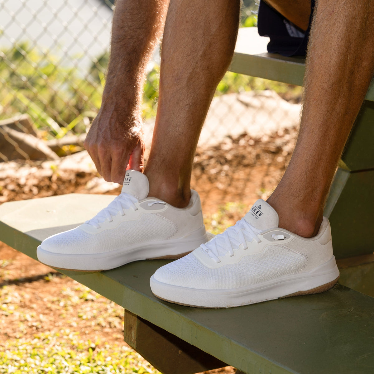 Shoreline Del Mar white sneakers facing right with man tying laces, showcasing lightweight, cushioned comfort and arch support