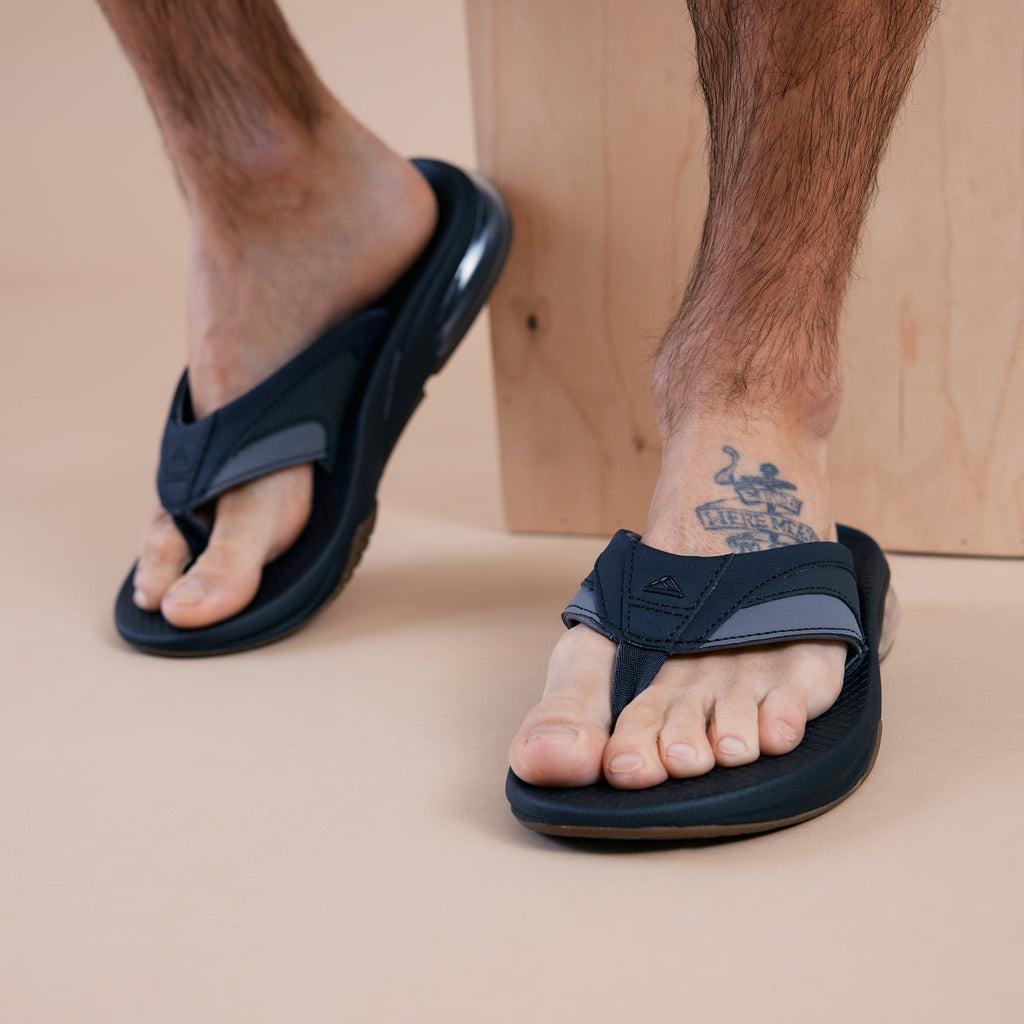 Fanning + men's black and gray sandals facing forward with soft-rebound cushioning and anatomical arch support, close-up of feet.