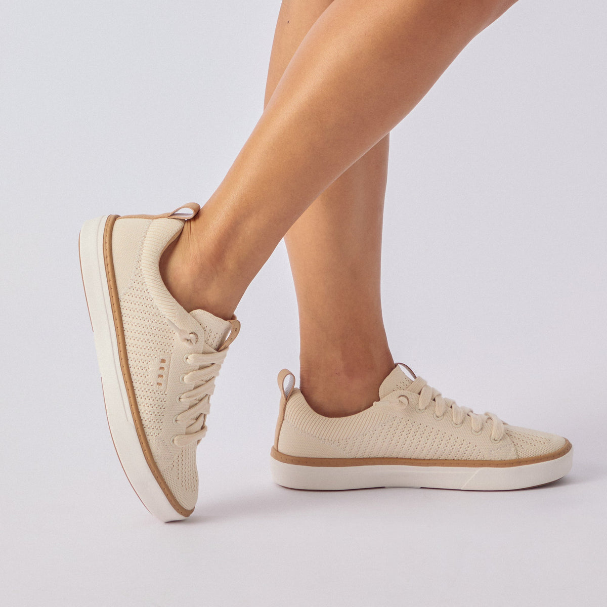 Side view of cream Lay Day Lite sneaker on woman's feet, showing cushioned, breathable upper and durable sole.