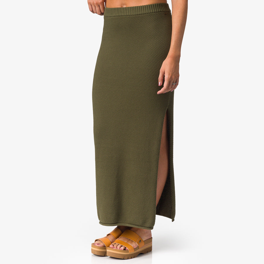 Up North Sweater Skirt in olive green knit fabric shown front left side with platform sandals facing forward, comfort apparel