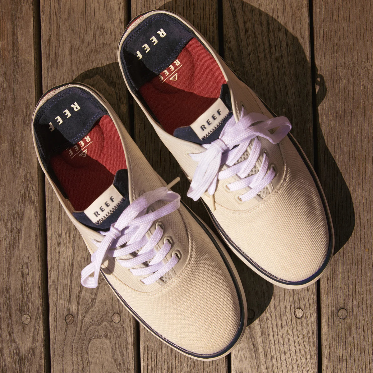 Top view of Neptune Lido men's canvas shoes facing forward on wooden deck, highlighting comfort and surf-inspired design.