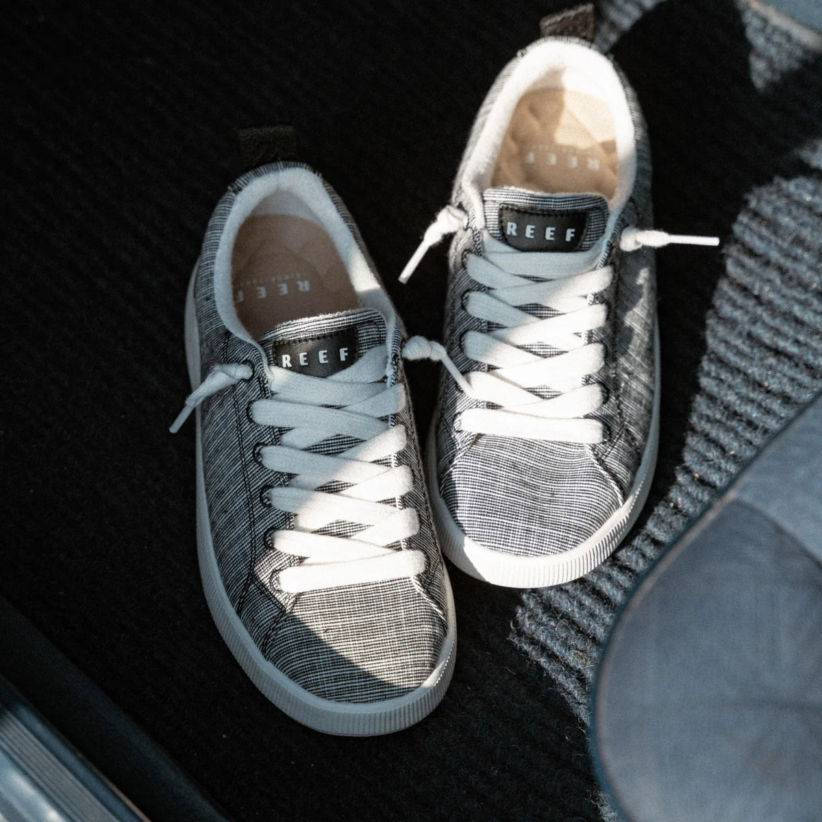 Neptune Alana women’s sneakers facing up, black and white with REEF logo, breathable, lightweight for everyday beach comfort.