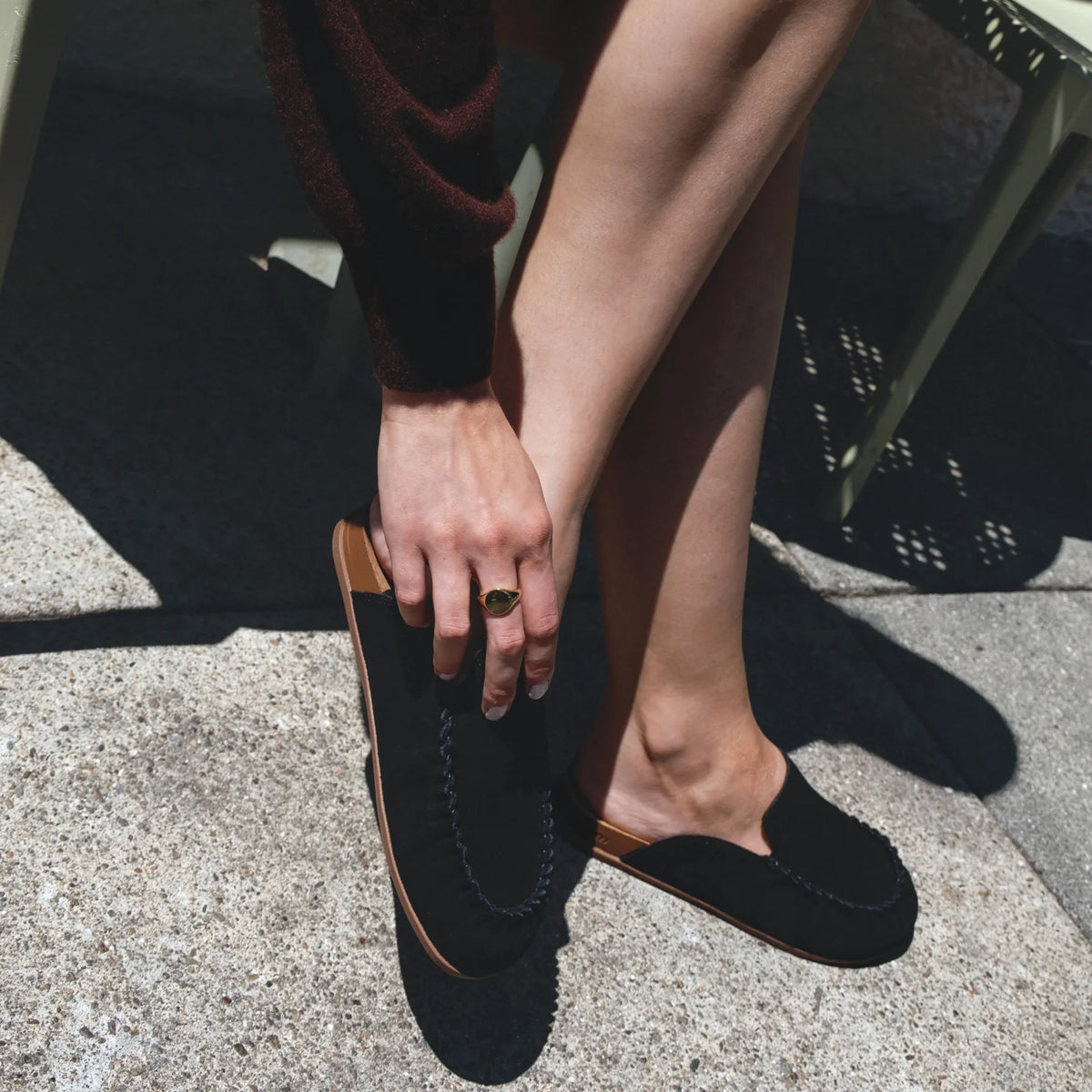 Woman wearing black Vista Myra facing forward, slip-on clog with suede upper, cushioning, and enhanced arch support for comfort.