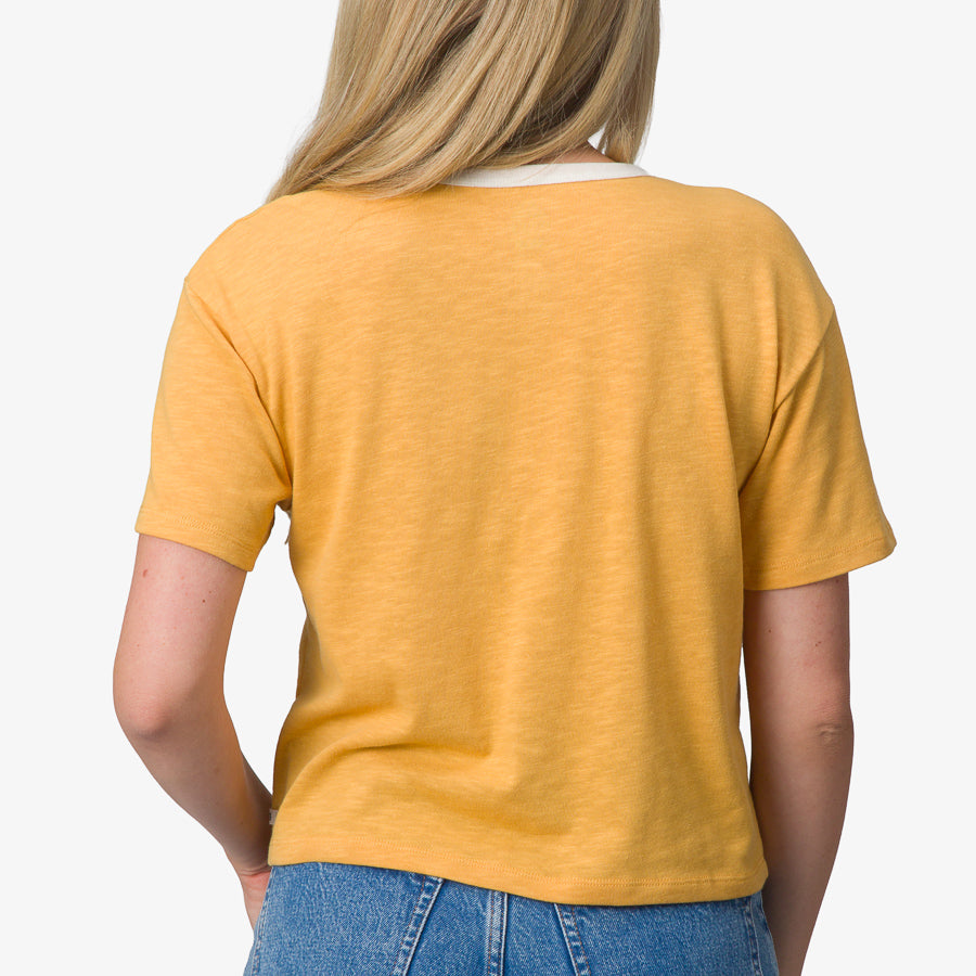 Woman wearing a honey gold Ringer Tee shown from back with short sleeves, soft fabric, and relaxed fit for comfort.