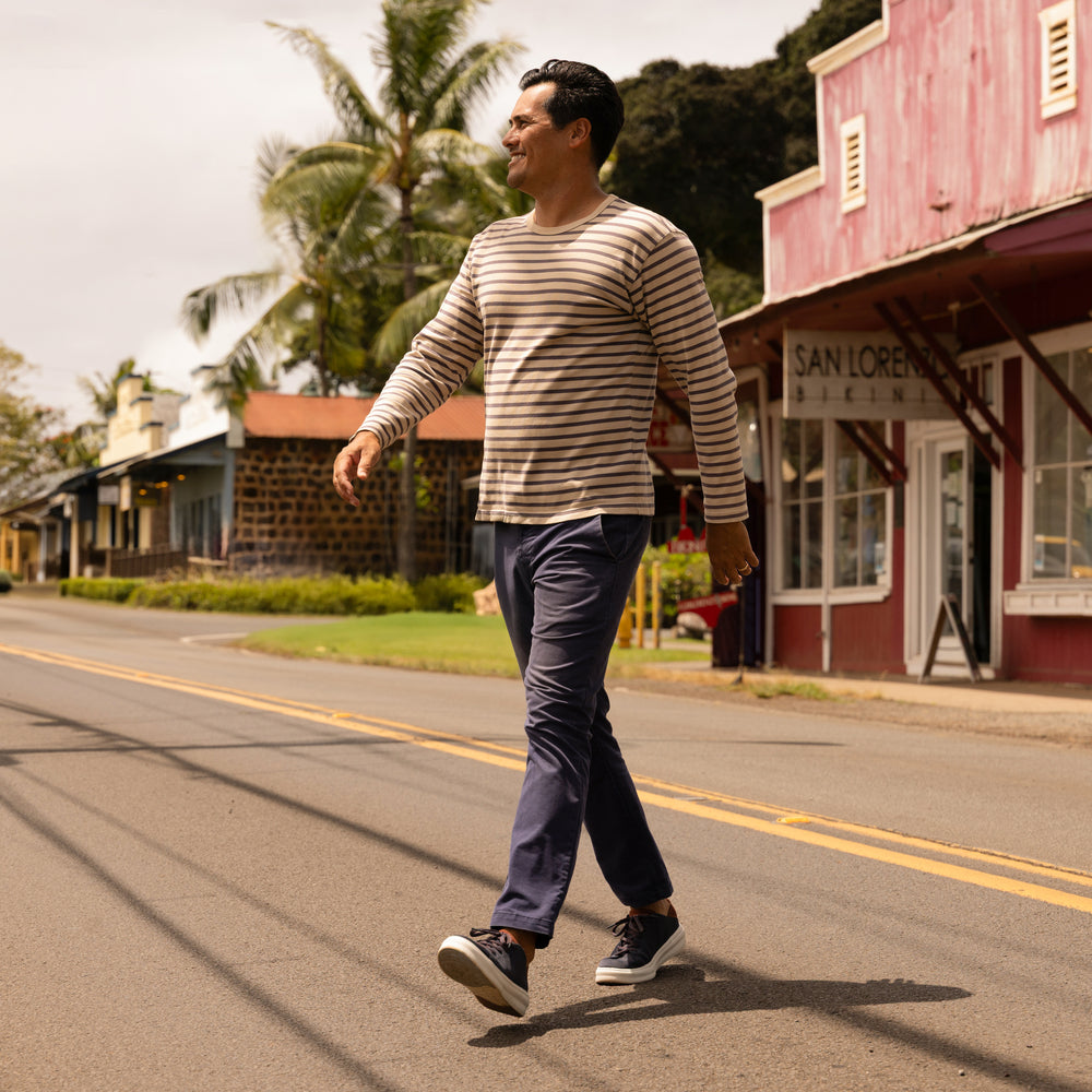 Man walking on street wearing Atlantic shoes facing right, featuring comfort and surf-inspired design in navy and cappuccino colors.