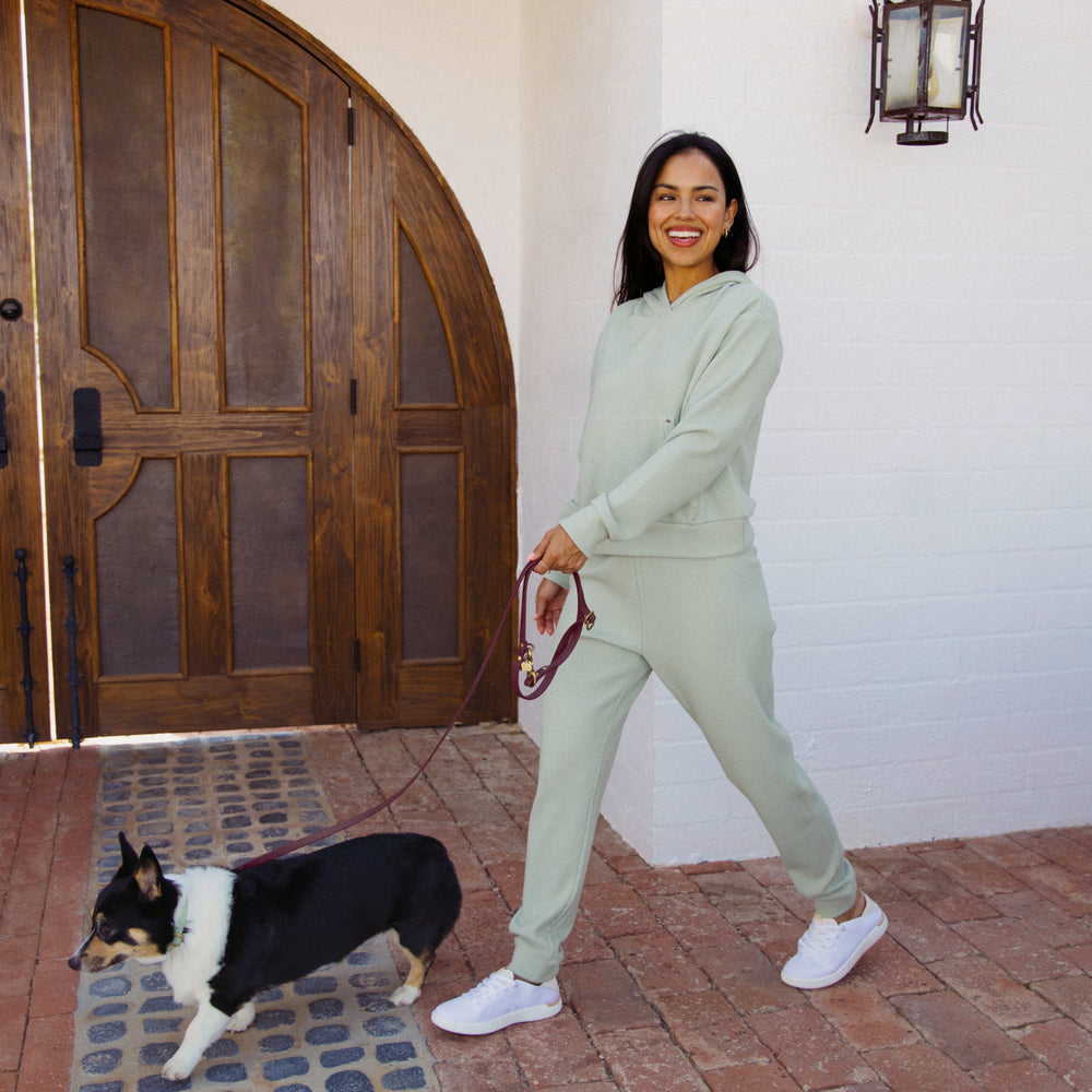 Woman wearing a desert sage Tina Thermal Hoodie walking a dog outside, showing full front view with comfortable apparel.
