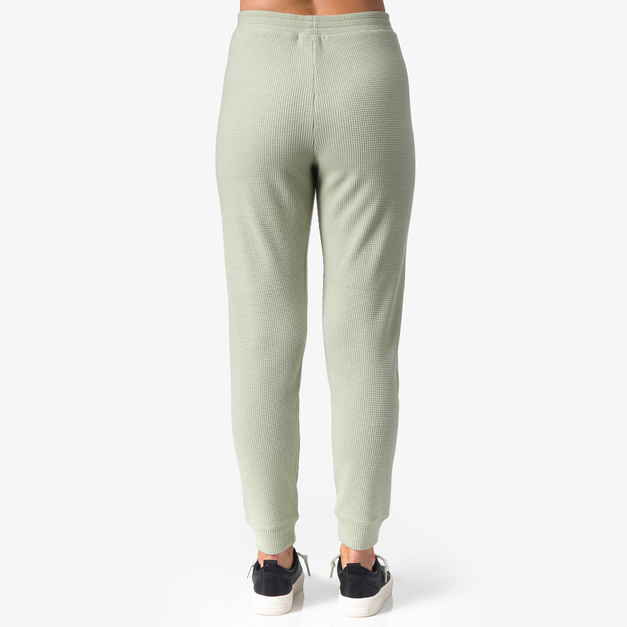 Back view of Tina Thermal Jogger in desert sage on woman wearing black sneakers, showcasing comfortable, beach-inspired apparel.