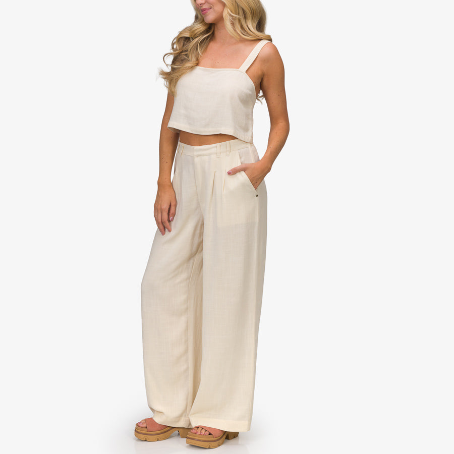 Woman wearing beige Tori Linen Pant standing with hands in pockets, facing slightly left, showing relaxed fit and comfort.