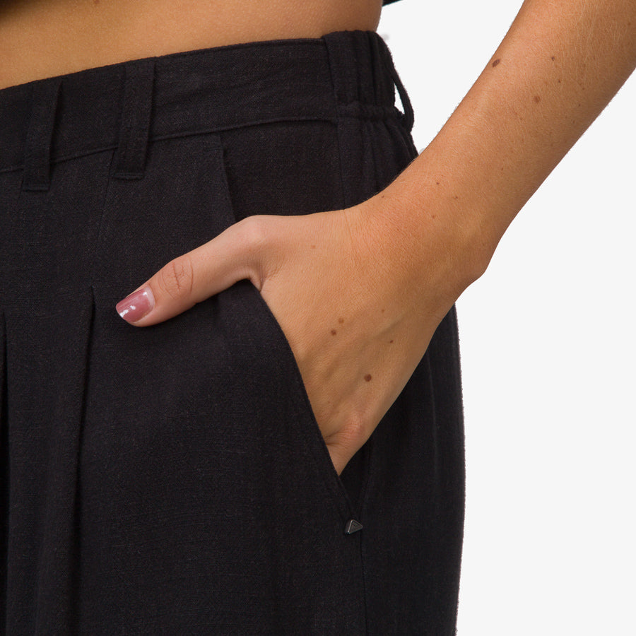 Close-up of a woman’s hand in the side pocket of black Tori Linen Pant, highlighting breathable, comfortable fabric.