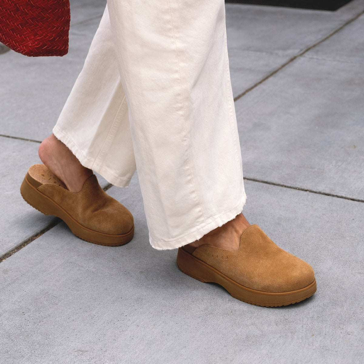 Woman walking wearing Vista Skye facing right, tan suede platform clogs with enhanced arch support for all-day comfort