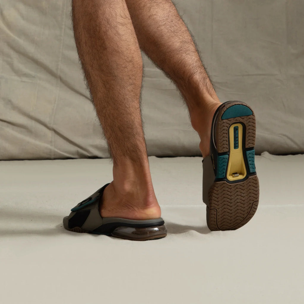 Fanning + Slide facing away, men's brown and spruce water-friendly slides with oversized airbag heel and REEFlex cushioning.